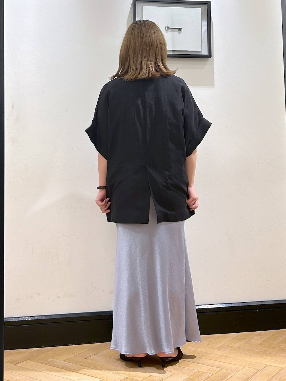 ブルー系のスカート、ブラウン系のパンプス、ホワイト系のシャツ/ブラウスを着用したレディースの夏コーディネートの7枚目の写真