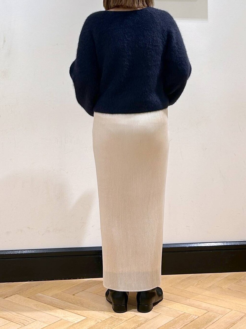 ブルー系のニット/セーター、ホワイト系のスカート、ブラック系のブーツを着用したレディースの秋コーディネートの8枚目の写真