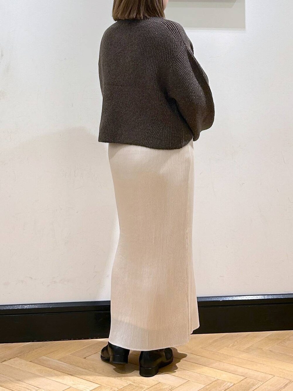 ブラウン系のニット/セーター、ホワイト系のスカート、ブラック系のブーツを着用したレディースの秋コーディネートの8枚目の写真