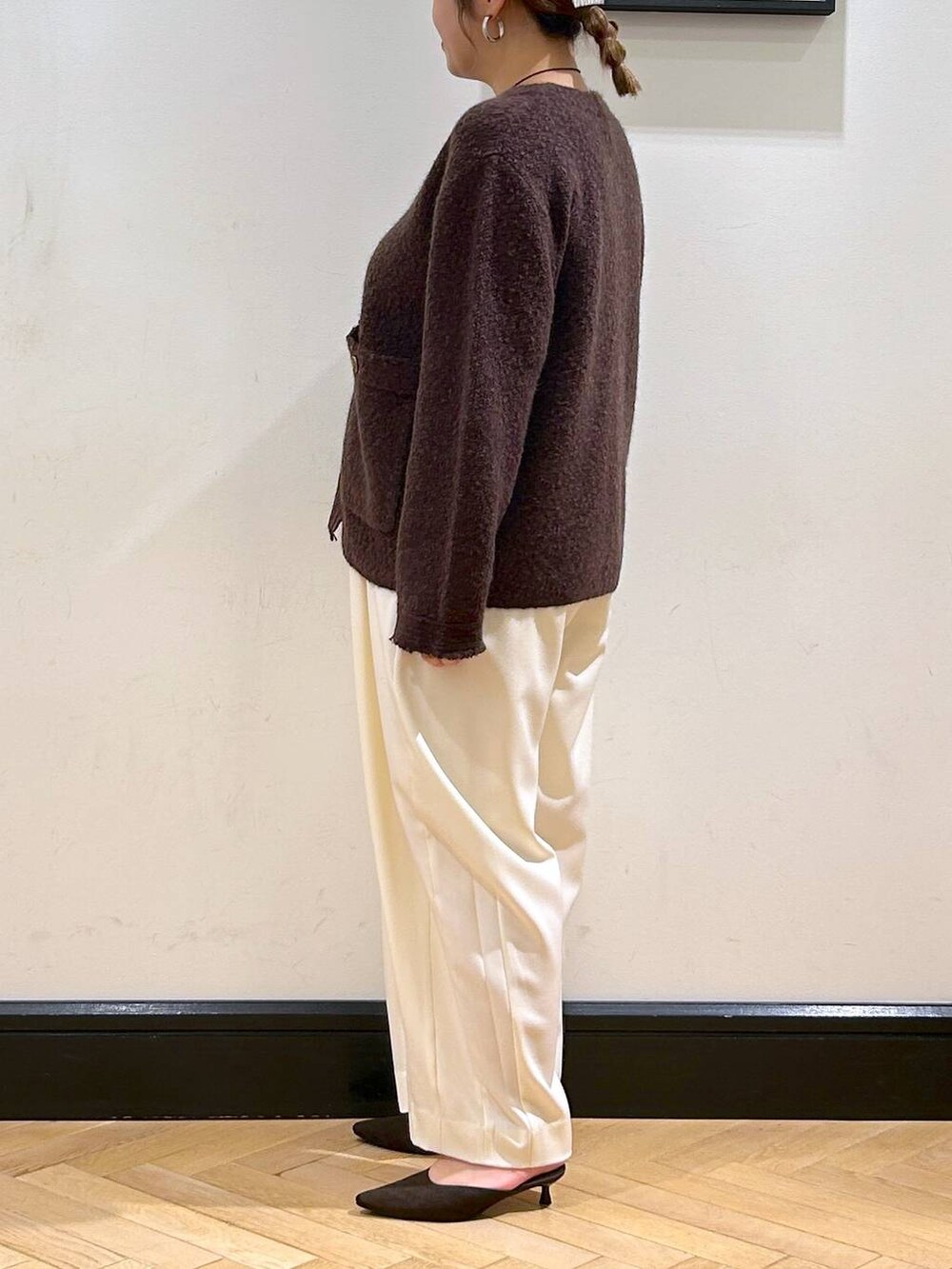 ホワイト系のスラックス、ブラウン系のパンプス、ベージュ系のショルダーバッグを着用したレディースの秋コーディネートの5枚目の写真