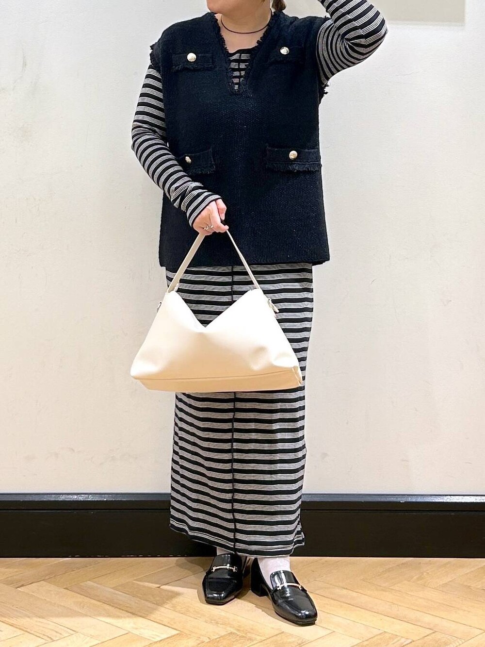 ブルー系のベスト、ブラック系のローファー、ベージュ系のショルダーバッグを着用したレディースの秋コーディネートの3枚目の写真