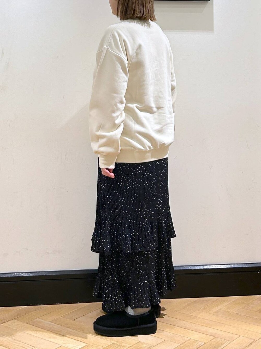 グレー系のスカート、ホワイト系のスウェット、ブラック系のスリッポンを着用したレディースの秋コーディネートの6枚目の写真