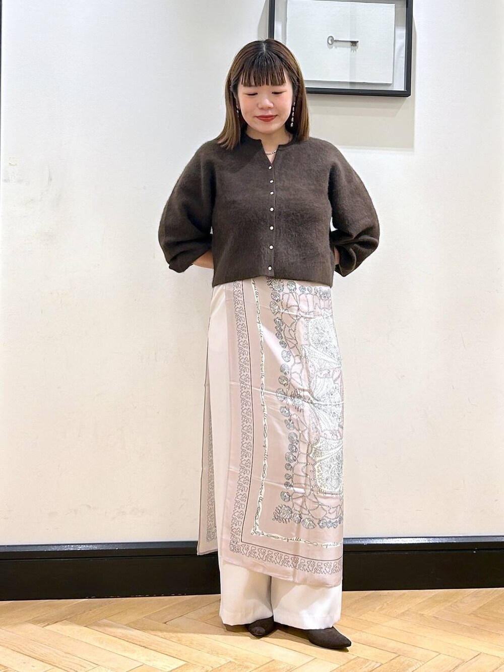 ブラウン系のカーディガン/ボレロ、ホワイト系のスラックス、ブラウン系のパンプスを着用したレディースの秋コーディネートの2枚目の写真