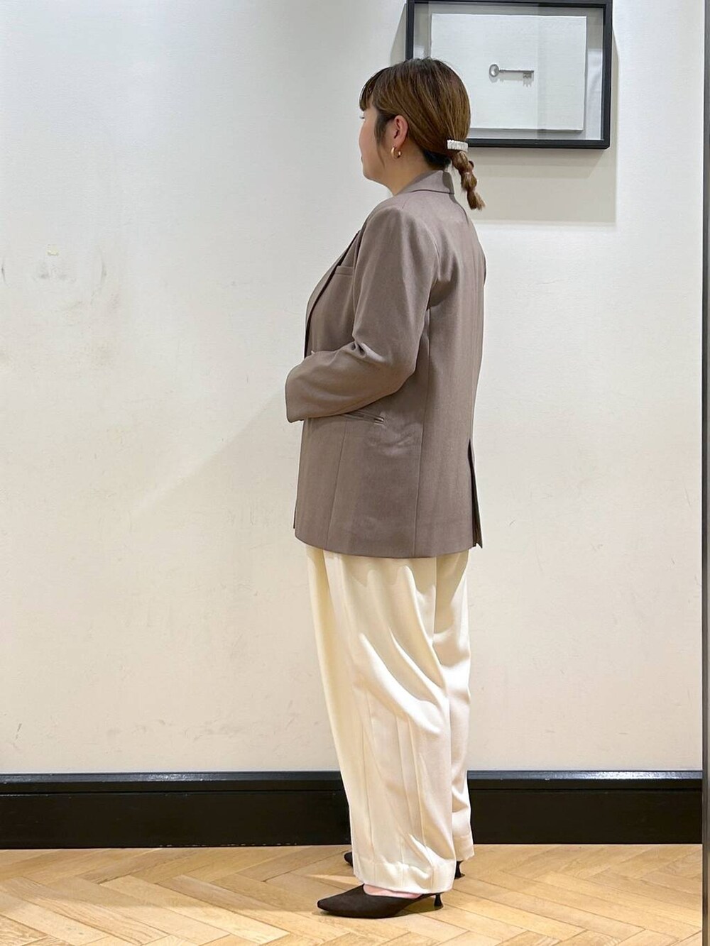 ホワイト系のスラックス、ブラウン系のパンプス、ブラック系のショルダーバッグを着用したレディースの秋コーディネートの7枚目の写真