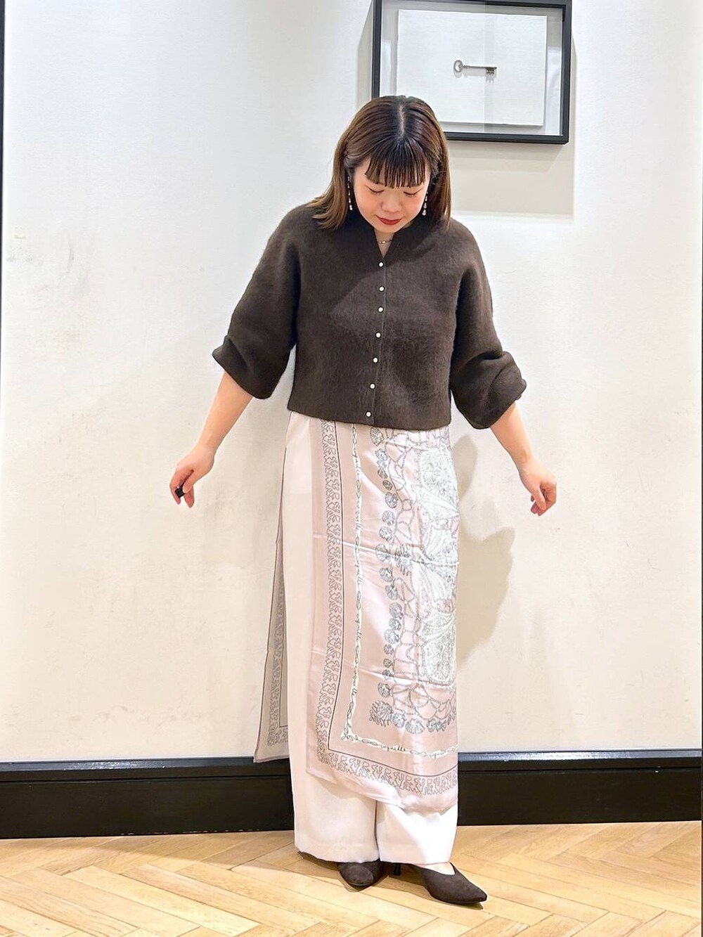 ブラウン系のカーディガン/ボレロ、ホワイト系のスラックス、ブラウン系のパンプスを着用したレディースの秋コーディネートの3枚目の写真