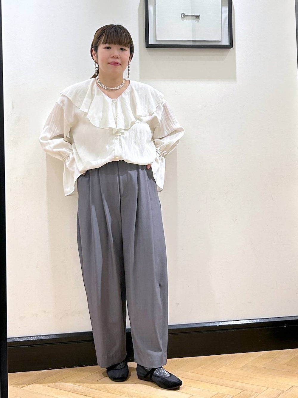 グレー系のスラックス、ブラック系のバレエシューズ、ホワイト系のシャツ/ブラウスを着用したレディースの秋コーディネートの2枚目の写真