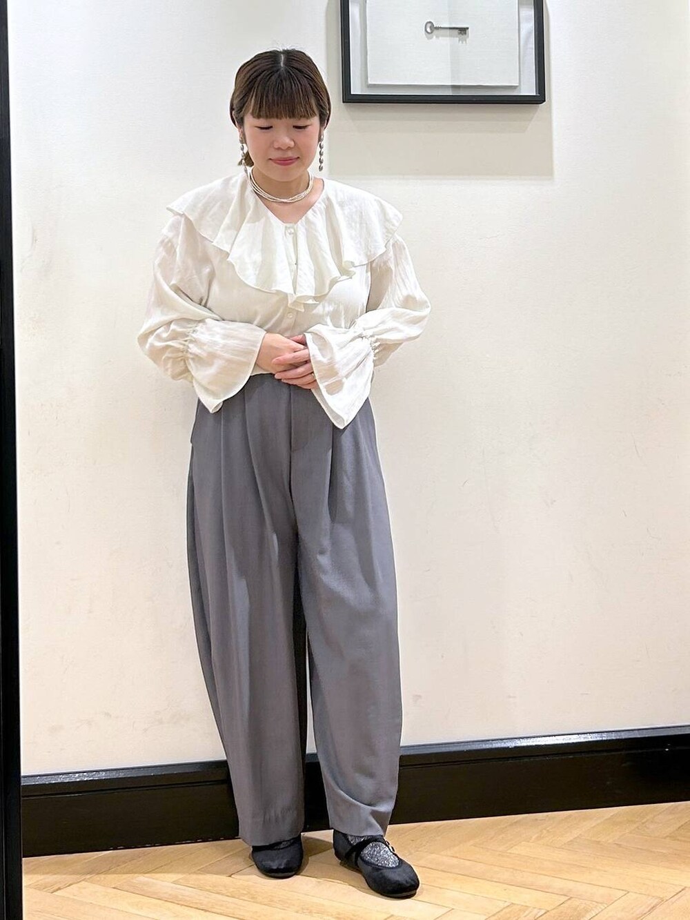 グレー系のスラックス、ブラック系のバレエシューズ、ホワイト系のシャツ/ブラウスを着用したレディースの秋コーディネートの4枚目の写真