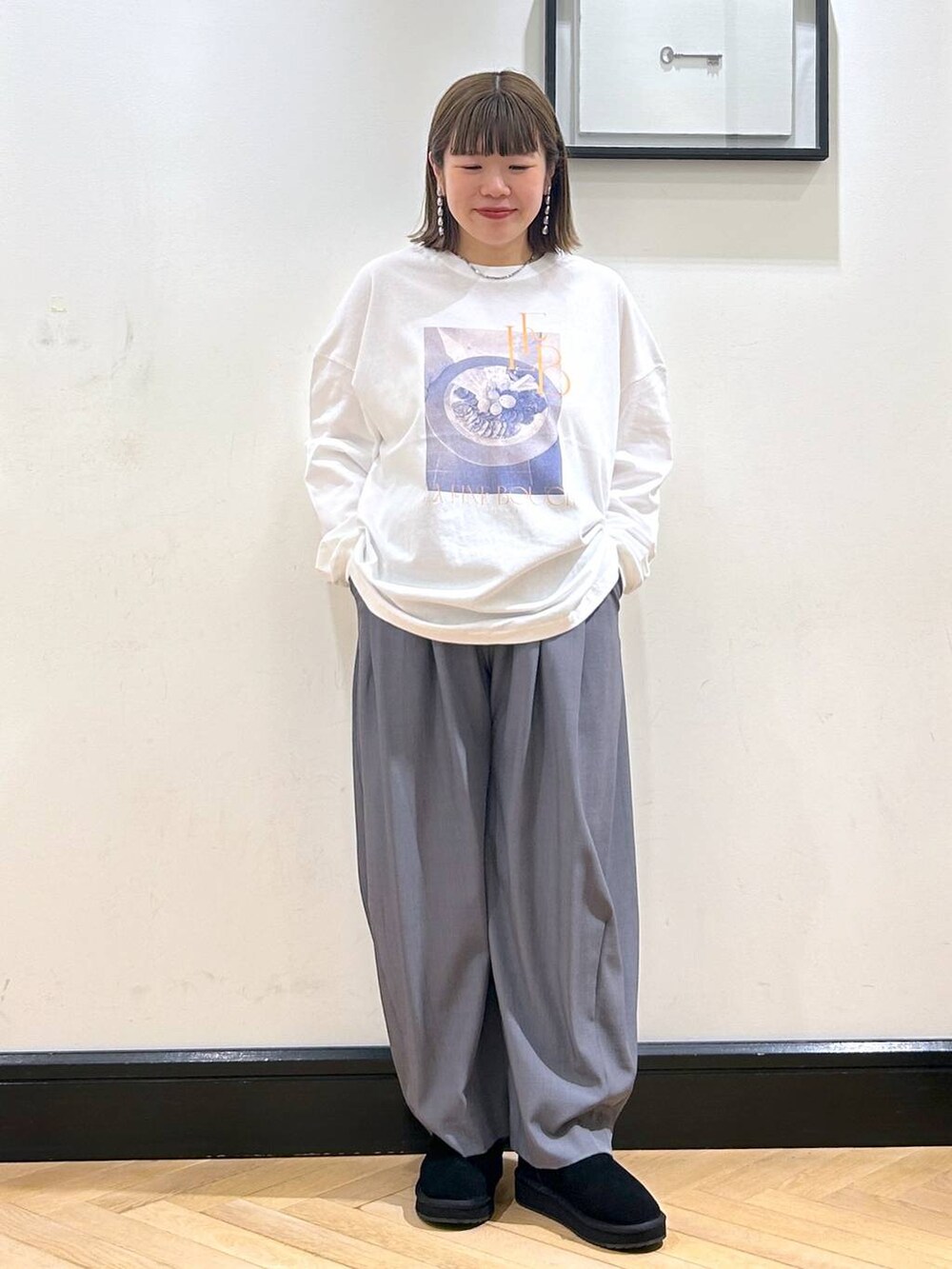 グレー系のスラックス、ホワイト系のTシャツ/カットソー、ブラック系のスリッポンを着用したレディースの秋コーディネートの3枚目の写真