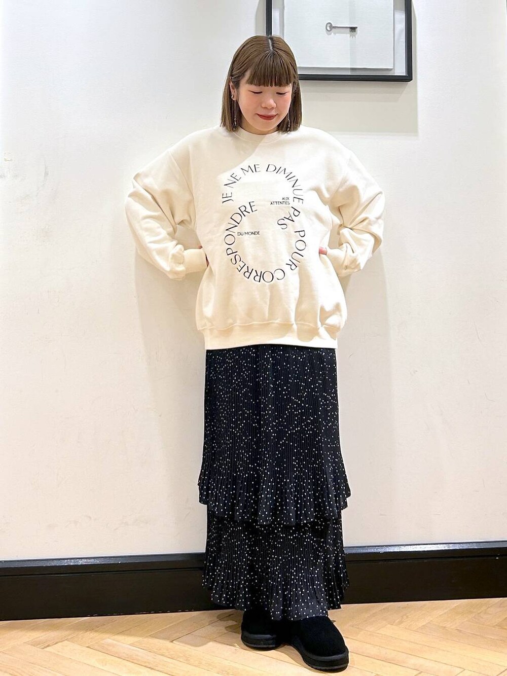 グレー系のスカート、ホワイト系のスウェット、ブラック系のスリッポンを着用したレディースの秋コーディネートの2枚目の写真