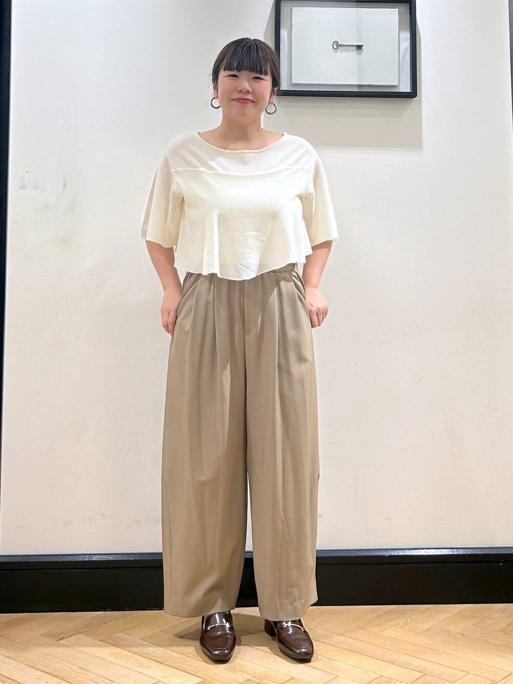 ベージュ系のスラックス、ブラウン系のローファー、ホワイト系のニット/セーターを着用したレディースの夏コーディネートの6枚目の写真