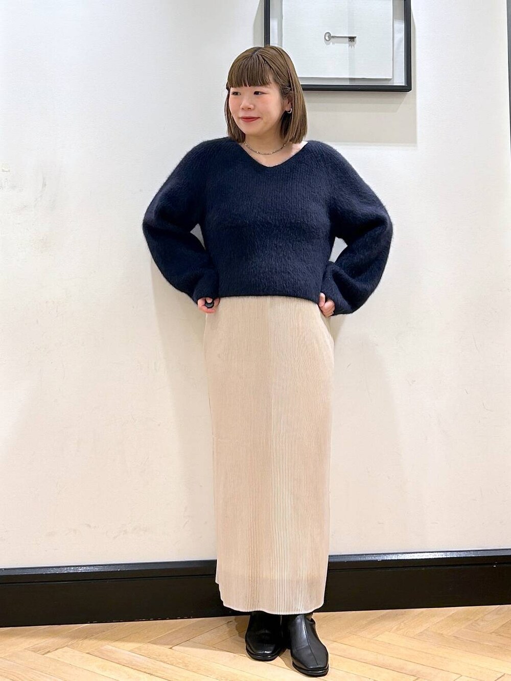 ブルー系のニット/セーター、ホワイト系のスカート、ブラック系のブーツを着用したレディースの秋コーディネートの2枚目の写真