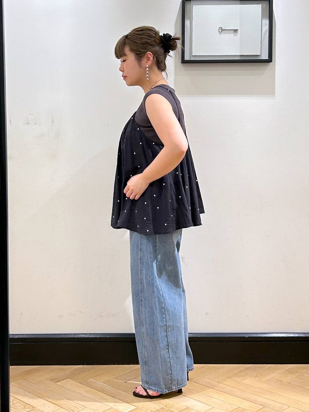 ブルー系のデニムパンツ、ブラウン系のサンダル、グレー系のタンクトップを着用したレディースの夏コーディネートの6枚目の写真