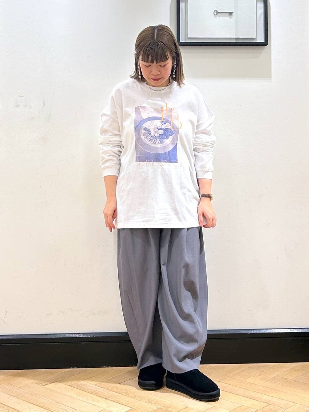 グレー系のスラックス、ホワイト系のTシャツ/カットソー、ブラック系のスリッポンを着用したレディースの秋コーディネートの4枚目の写真