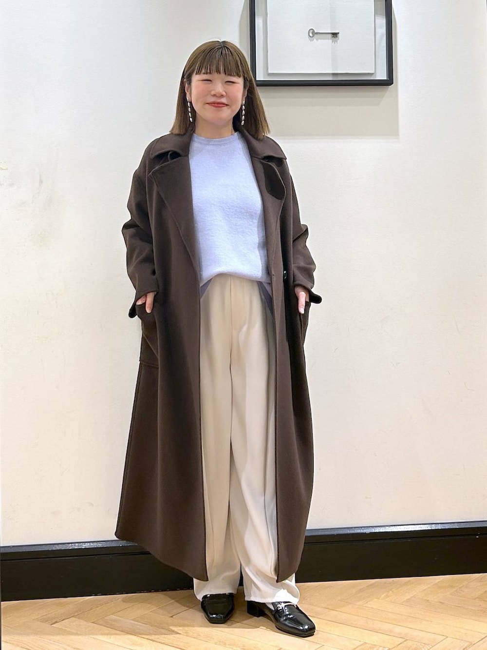 ブラウン系のステンカラーコート、ブラック系のローファー、ブルー系のニット/セーターを着用したレディースの秋コーディネートの3枚目の写真