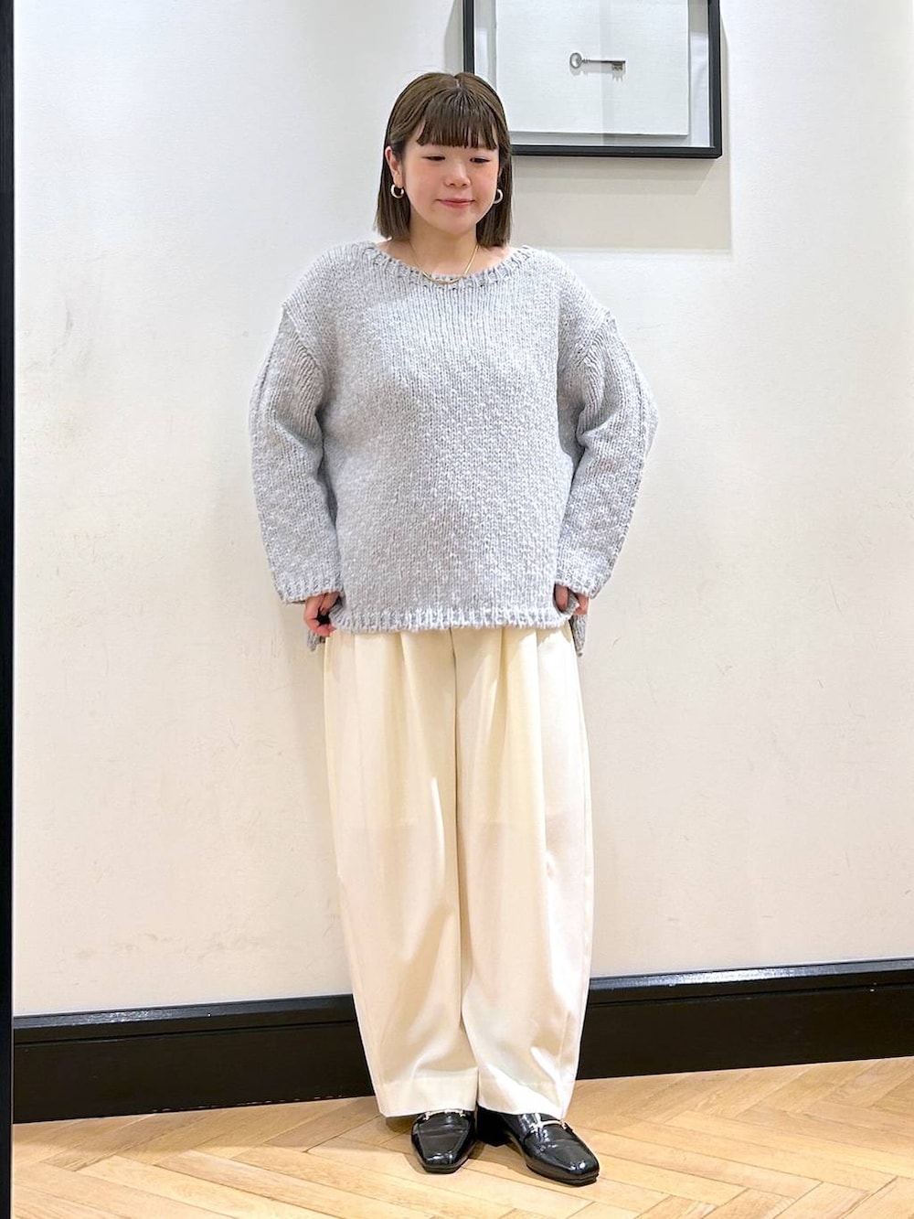 ホワイト系のスラックス、ブラック系のローファー、グレー系のニット/セーターを着用したレディースの秋コーディネートの3枚目の写真