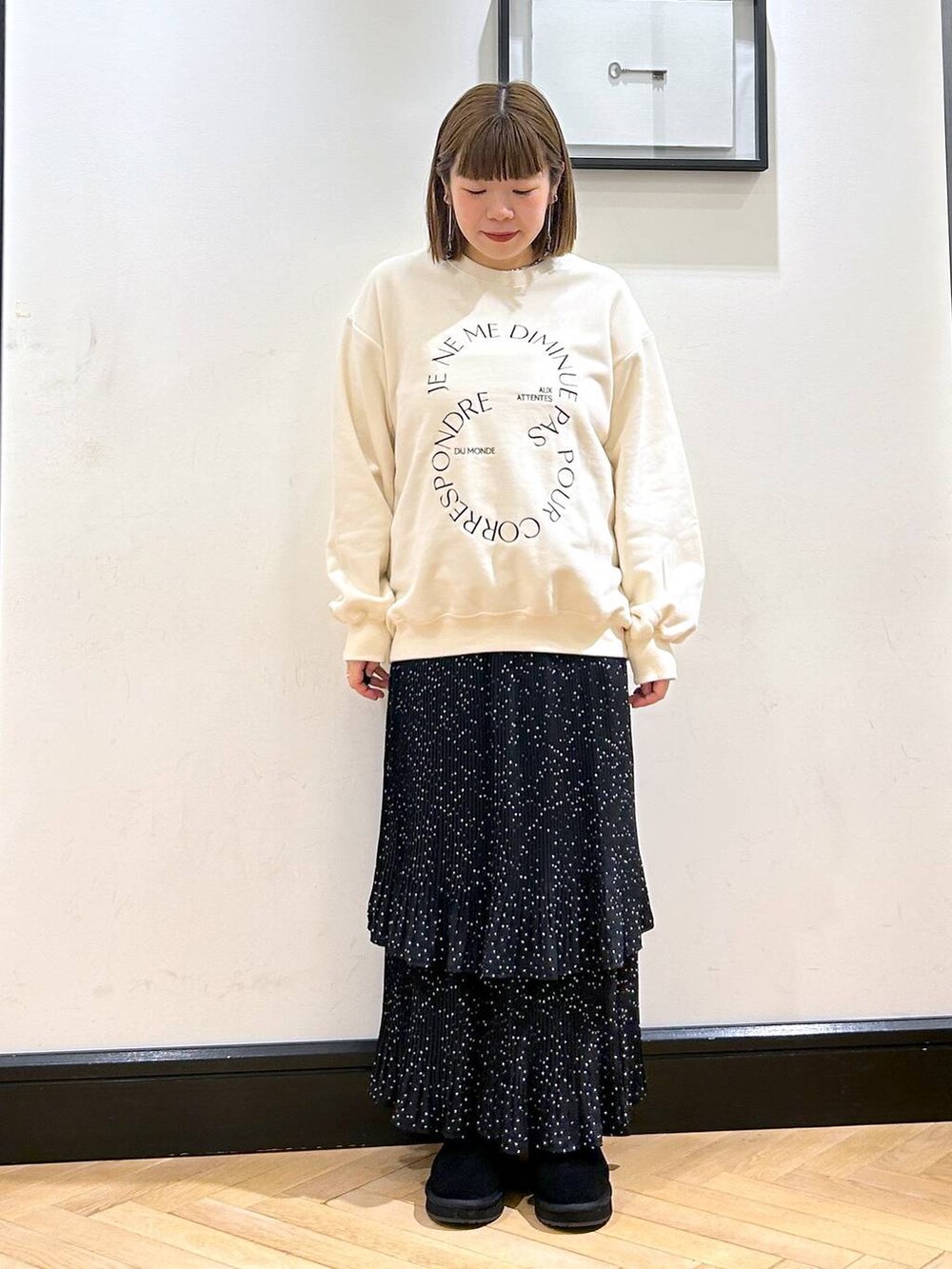 グレー系のスカート、ホワイト系のスウェット、ブラック系のスリッポンを着用したレディースの秋コーディネートの4枚目の写真