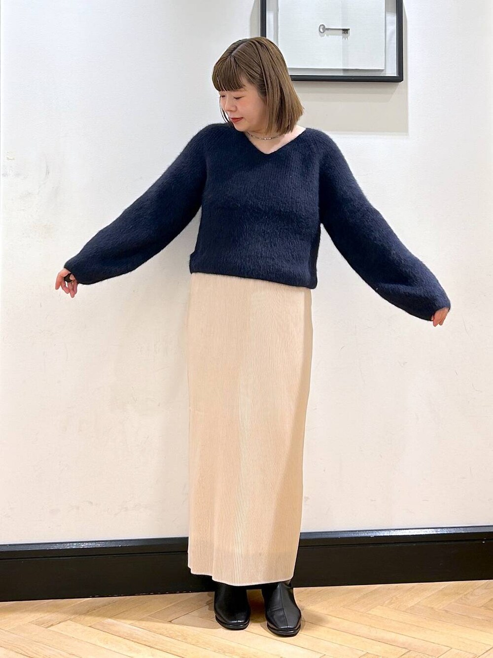 ブルー系のニット/セーター、ホワイト系のスカート、ブラック系のブーツを着用したレディースの秋コーディネートの4枚目の写真