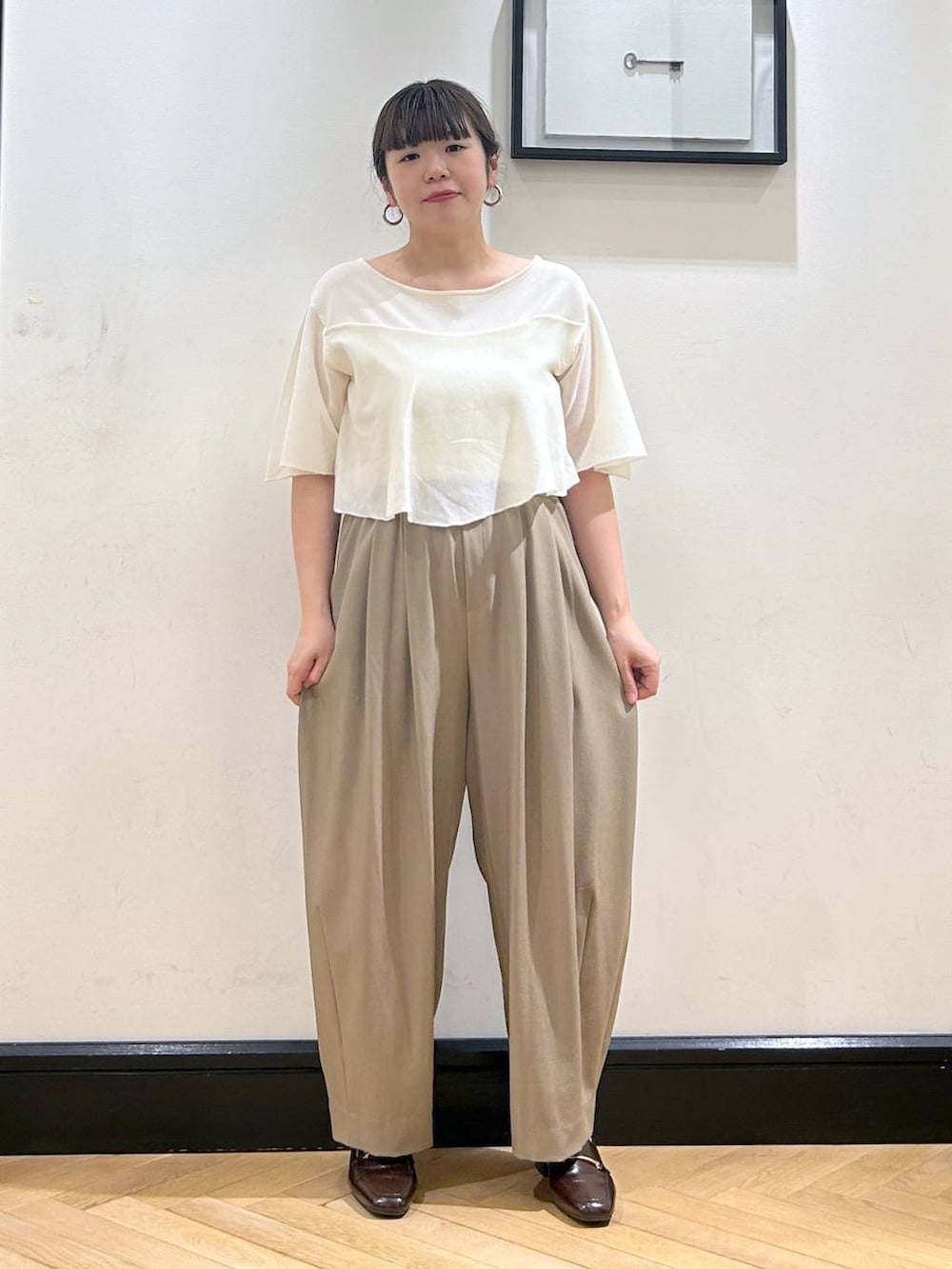 ベージュ系のスラックス、ブラウン系のローファー、ホワイト系のニット/セーターを着用したレディースの夏コーディネートの7枚目の写真