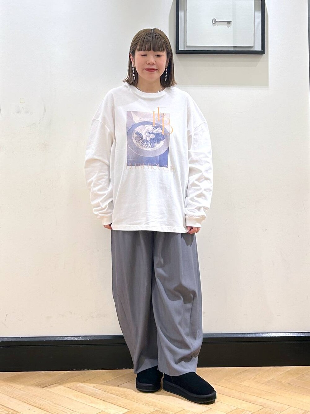 グレー系のスラックス、ホワイト系のTシャツ/カットソー、ブラック系のスリッポンを着用したレディースの秋コーディネートの5枚目の写真