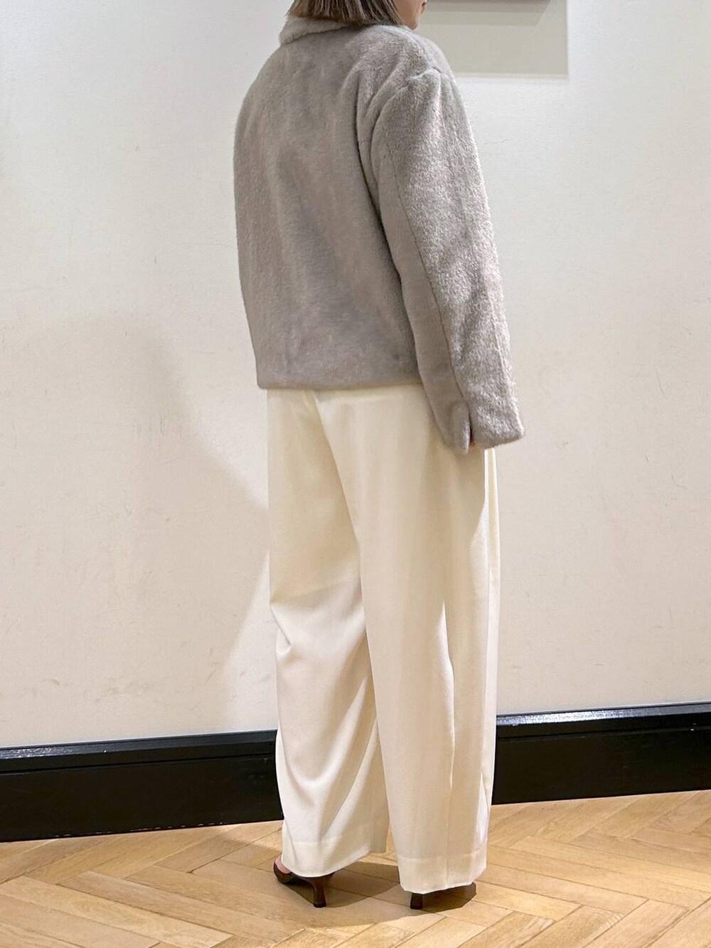 ホワイト系のスラックス、グレー系のその他アウター、ゴールド系のネックレスを着用したレディースの秋コーディネートの6枚目の写真