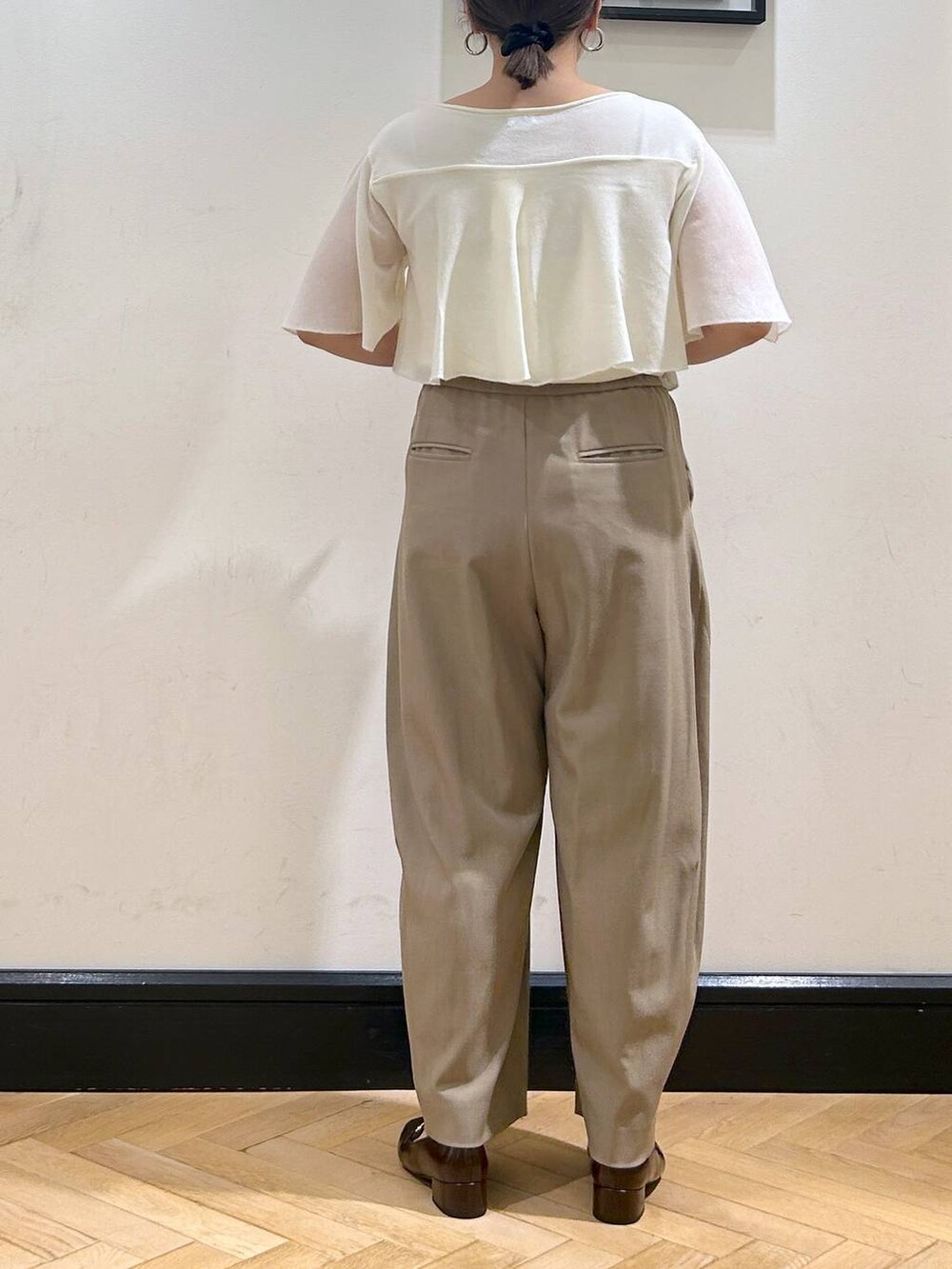 ベージュ系のスラックス、ブラウン系のローファー、ホワイト系のニット/セーターを着用したレディースの夏コーディネートの9枚目の写真