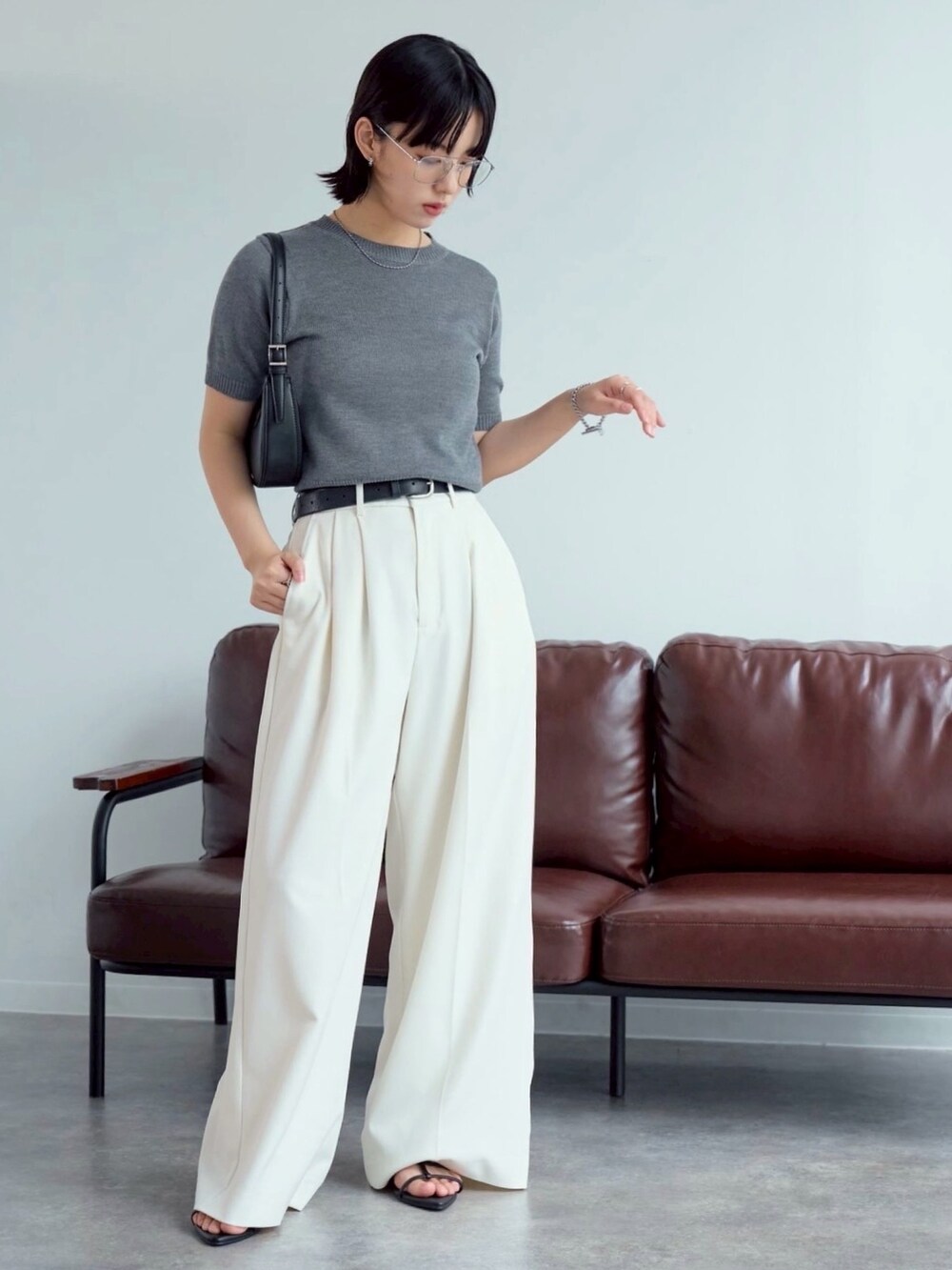 グレー系のニット/セーター、ブラック系のサンダル、ホワイト系のスラックスを着用したレディースの夏コーディネートの2枚目の写真