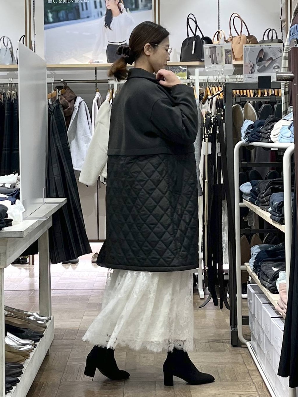 ブラウン系のステンカラーコート、ホワイト系のニット/セーター、ブラック系のショルダーバッグを着用したレディースの秋コーディネートの2枚目の写真