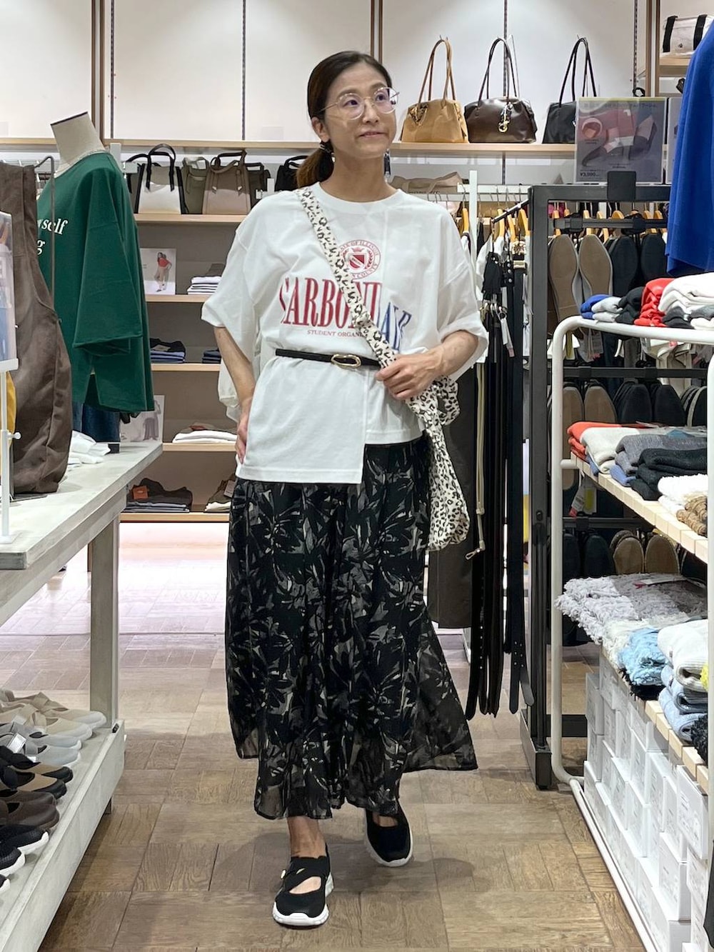 ブラック系のスニーカー、ブラウン系のトートバッグ、ブラック系のスカートを着用したレディースの秋コーディネートの2枚目の写真