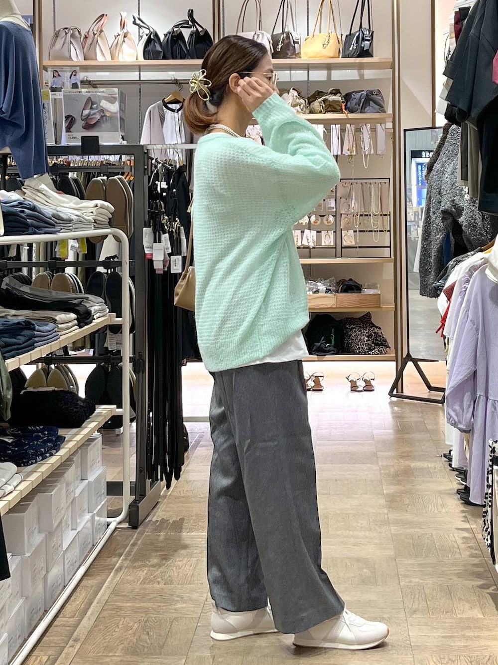 グレー系のその他パンツ、ベージュ系のスニーカー、グリーン系のニット/セーターを着用したレディースの秋コーディネートの2枚目の写真