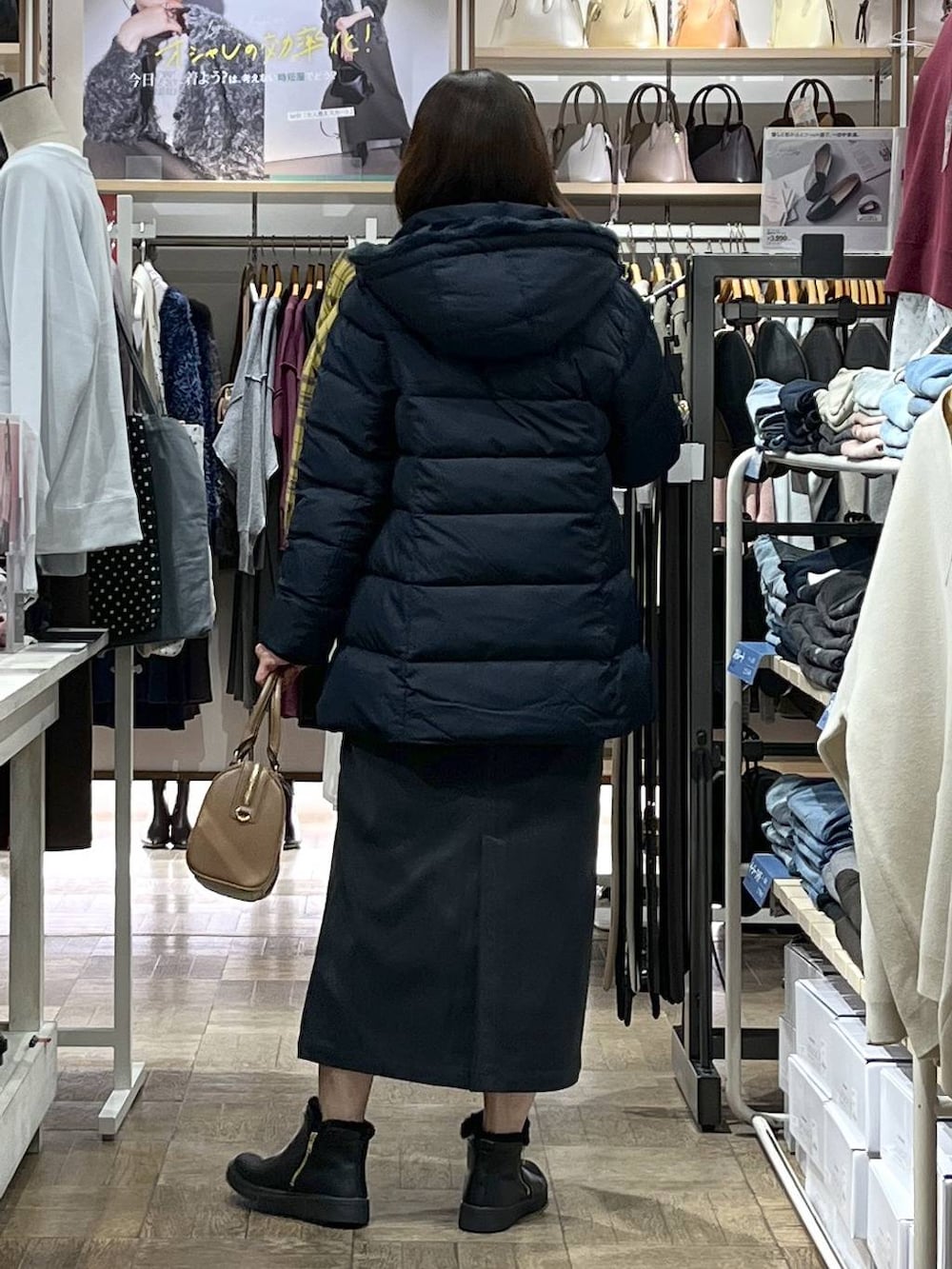 ブルー系のダウンジャケット/コート、グレー系のスカート、シルバー系のニット/セーターを着用したレディースの冬コーディネートの3枚目の写真