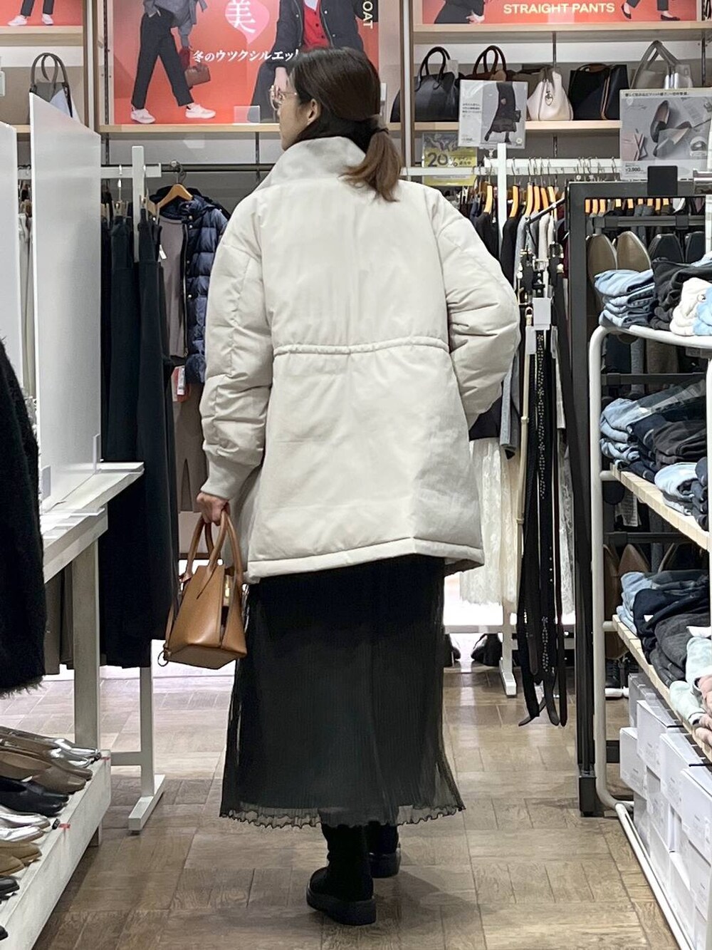 ブラウン系のショルダーバッグ、ベージュ系のダウンジャケット/コート、グレー系のワンピースを着用したレディースの秋コーディネートの3枚目の写真