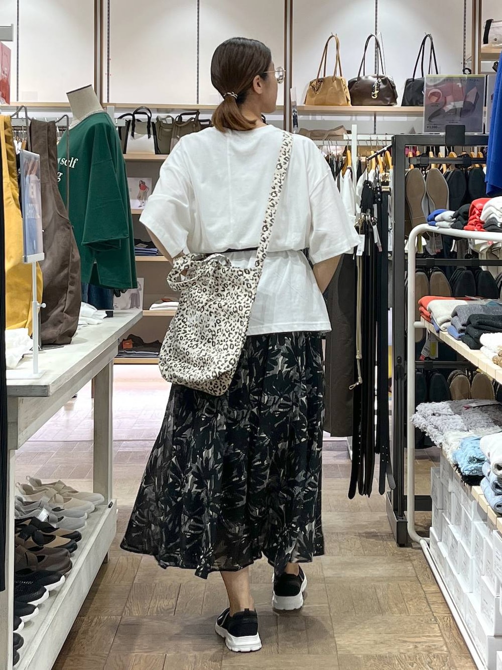 ブラック系のスニーカー、ブラウン系のトートバッグ、ブラック系のスカートを着用したレディースの秋コーディネートの3枚目の写真