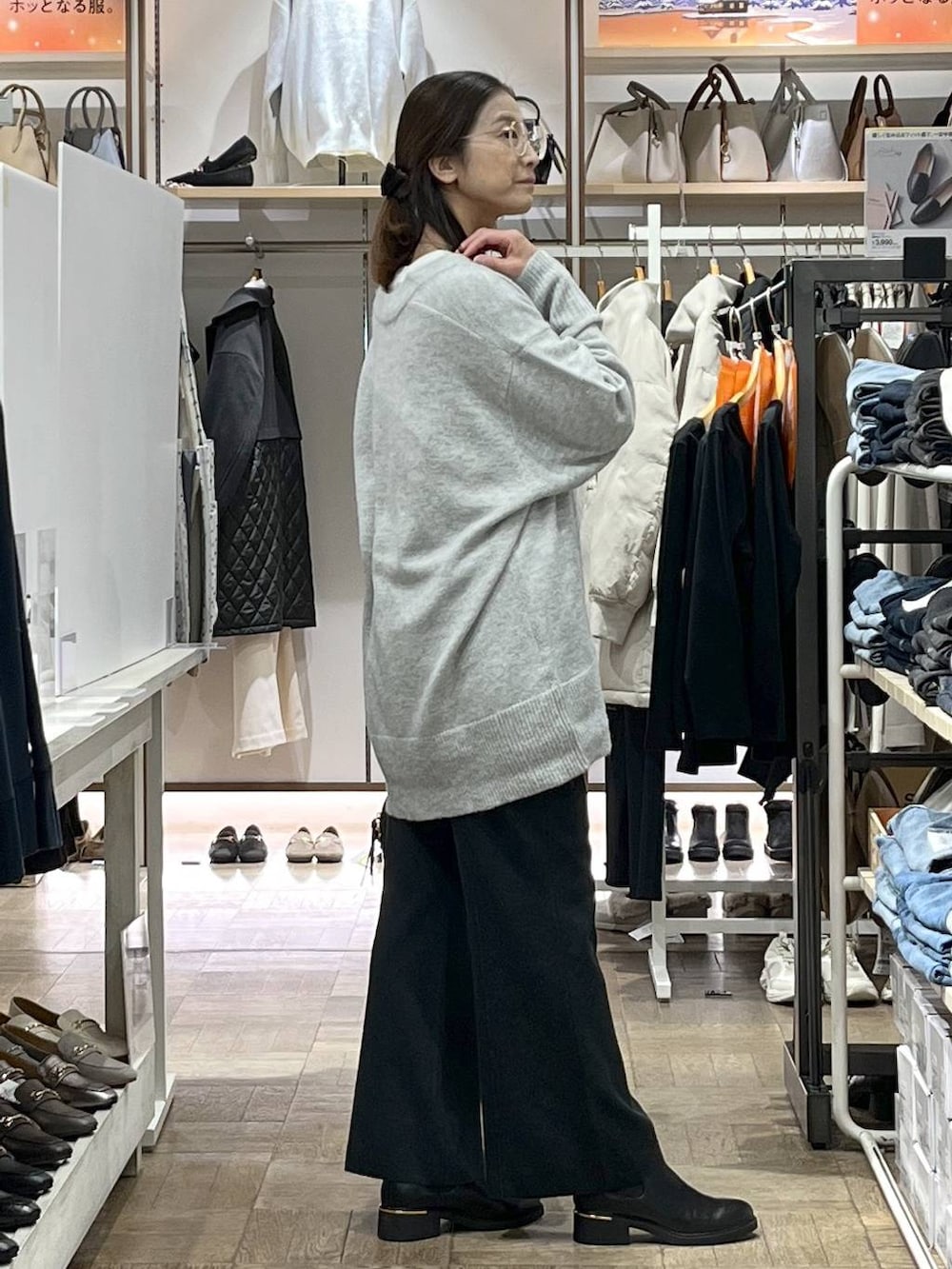 グレー系のニット/セーター、ホワイト系のTシャツ/カットソー、ブラック系のボストンバッグを着用したレディースの冬コーディネートの2枚目の写真