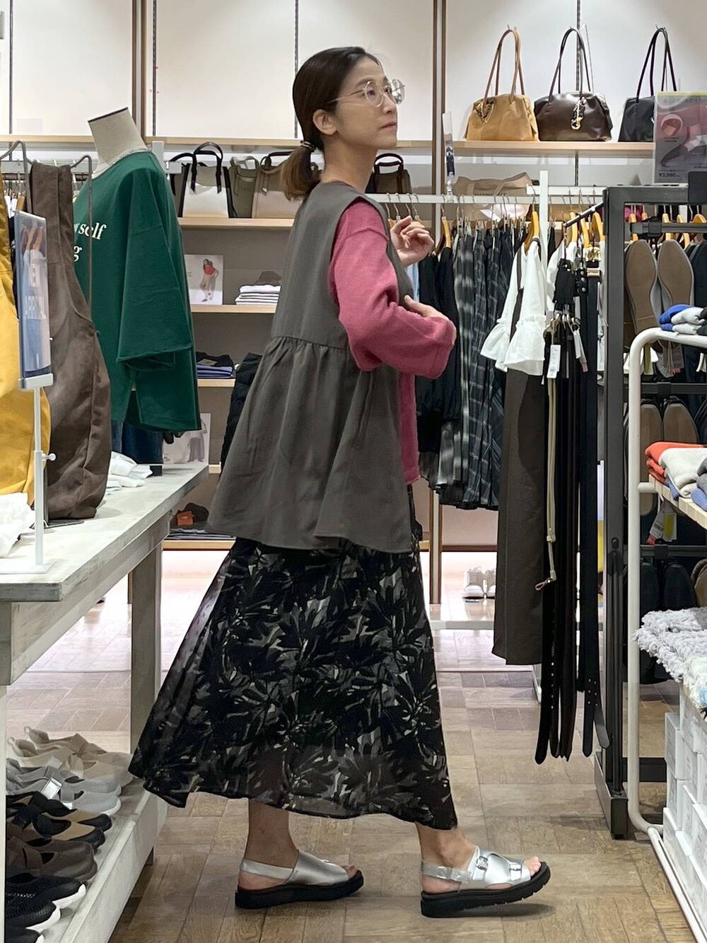 シルバー系のサンダル、ブラウン系のベスト、ブラック系のスカートを着用したレディースの秋コーディネートの2枚目の写真