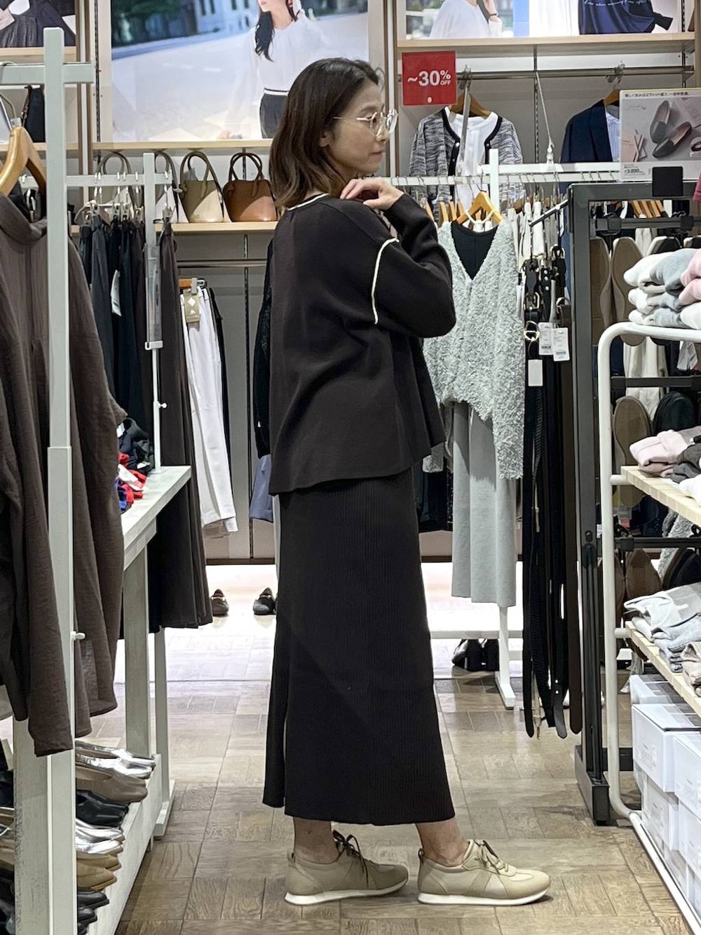 ベージュ系のスニーカー、ブラウン系のワンピース、ブラック系のボストンバッグを着用したレディースの秋コーディネートの2枚目の写真