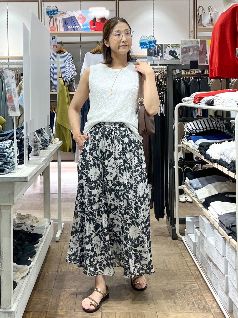 ブラック系のスカート、ブラウン系のショルダーバッグ、ホワイト系のタンクトップを着用したレディースの夏コーディネートの2枚目の写真