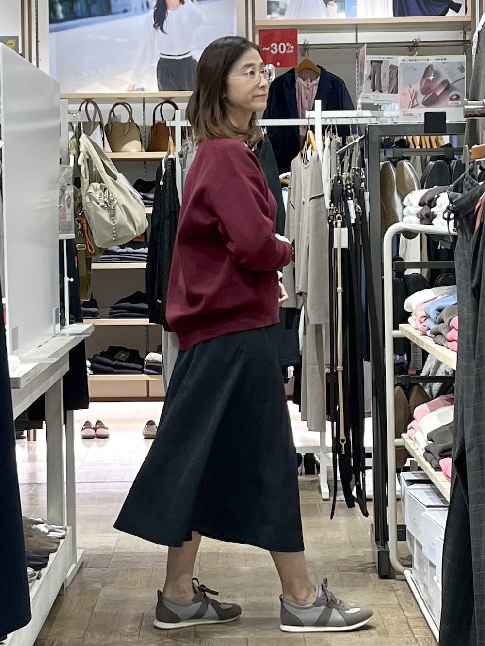 レッド系のスウェット、グレー系のスカート、グレー系のスニーカーを着用したレディースの秋コーディネートの2枚目の写真