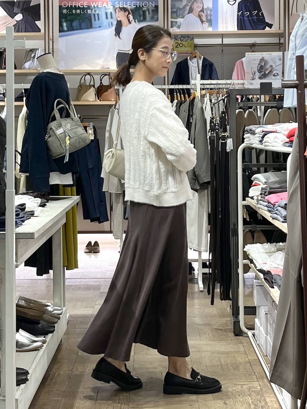 ブラウン系のスカート、ブラック系のローファー、ベージュ系のショルダーバッグを着用したレディースの秋コーディネートの2枚目の写真