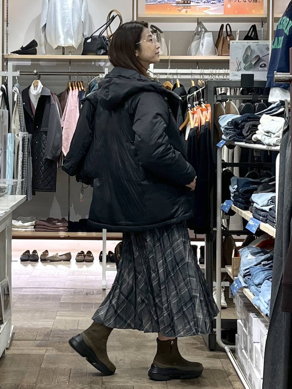 ブラック系のダウンジャケット/コート、ブラウン系のブーツ、ベージュ系のニット/セーターを着用したレディースの冬コーディネートの2枚目の写真