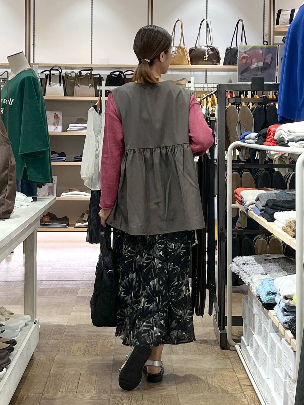 シルバー系のサンダル、ブラウン系のベスト、ブラック系のスカートを着用したレディースの秋コーディネートの3枚目の写真