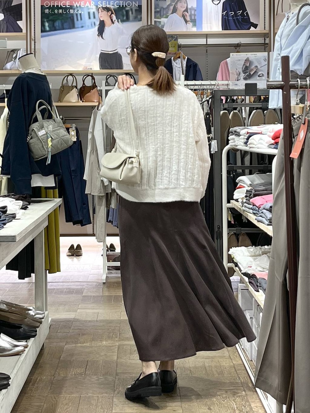 ブラウン系のスカート、ブラック系のローファー、ベージュ系のショルダーバッグを着用したレディースの秋コーディネートの3枚目の写真