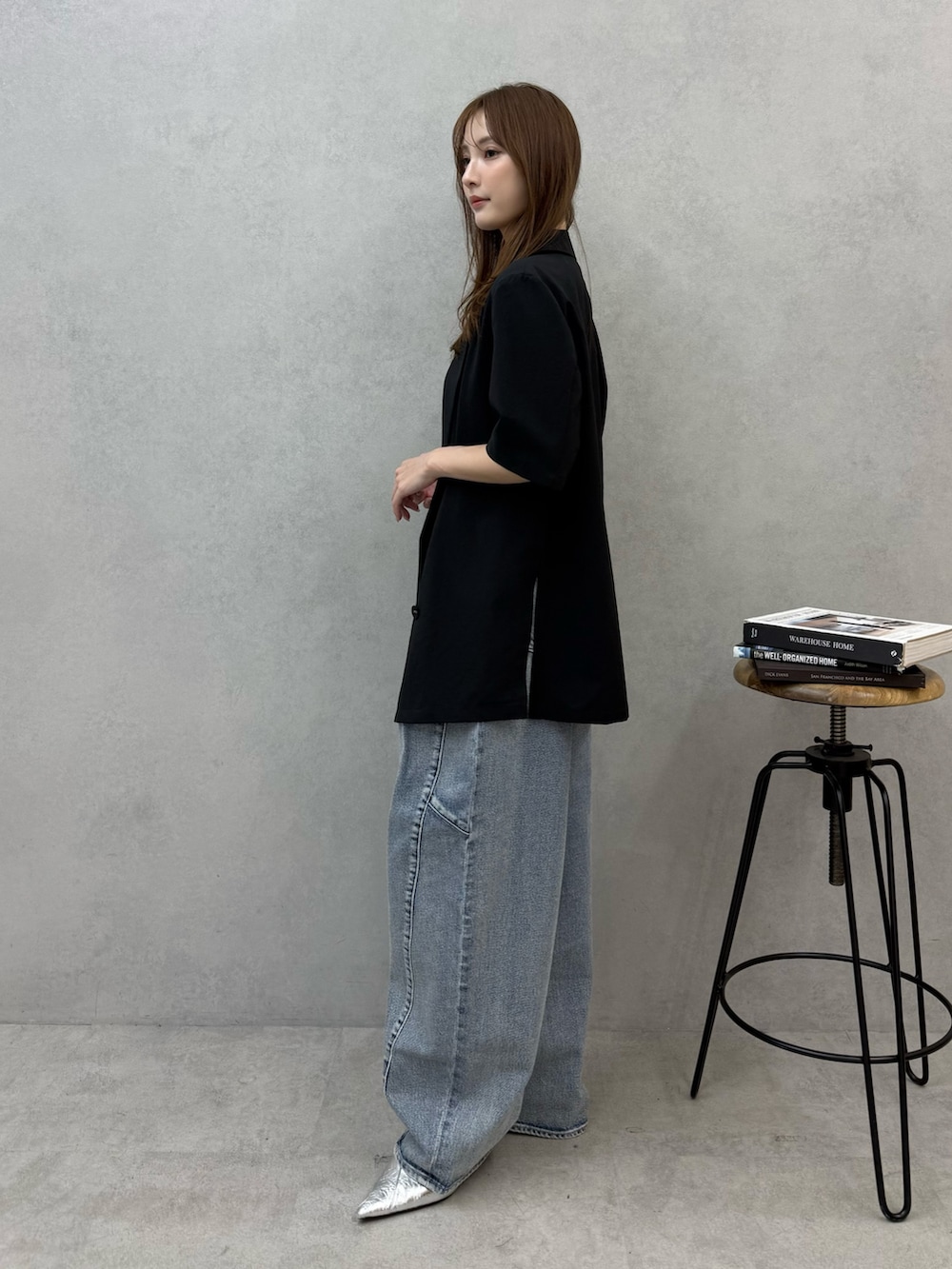 ブルー系のデニムパンツ、ブラック系のテーラードジャケット、シルバー系のパンプスを着用したレディースの春コーディネートの2枚目の写真