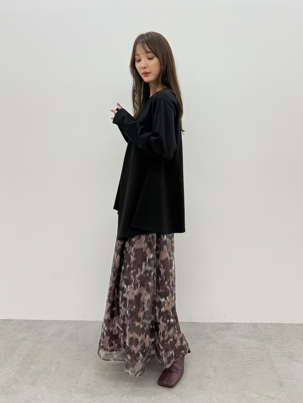 ブラック系のTシャツ/カットソー、ブラウン系のスカートを着用したレディースの秋コーディネートの2枚目の写真