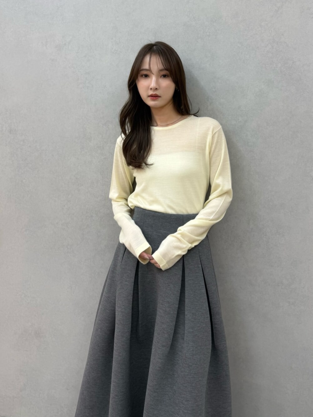 イエロー系のニット/セーター、グレー系のスカート、ブラック系のパンプスを着用したレディースの冬コーディネートの6枚目の写真