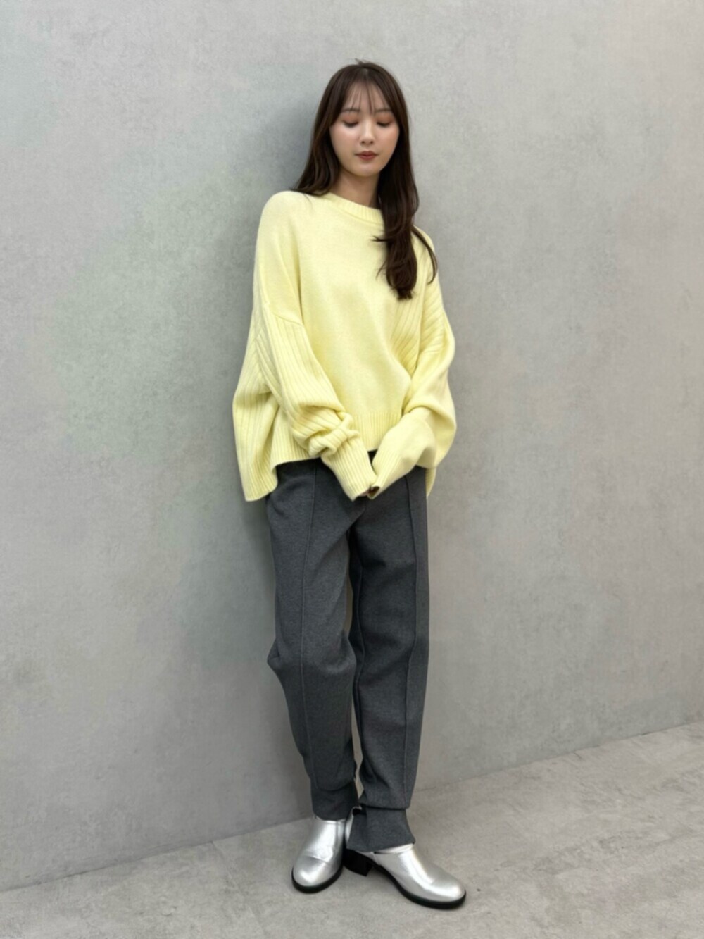 イエロー系のニット/セーター、グレー系のその他パンツ、シルバー系のパンプスを着用したレディースの秋コーディネートの2枚目の写真
