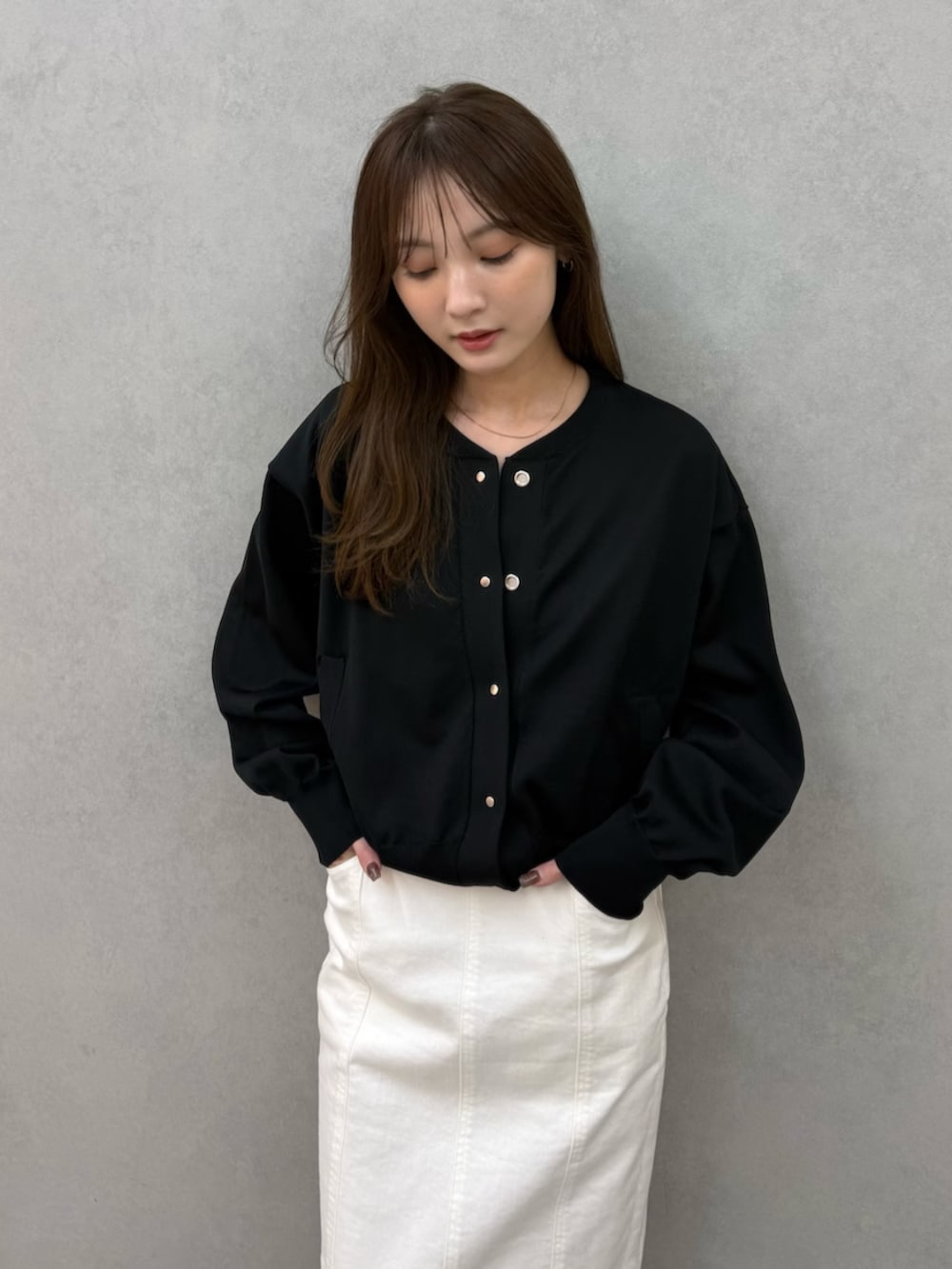 ブラック系のカーディガン/ボレロ、ブラック系のパンプス、ホワイト系のスカートを着用したレディースの春コーディネートの5枚目の写真