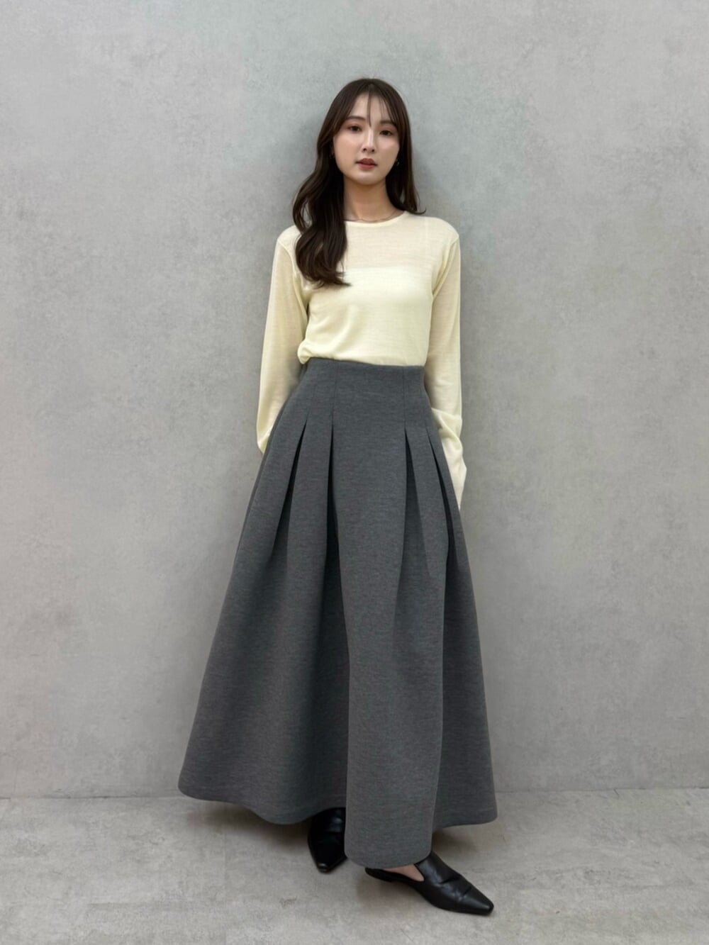 イエロー系のニット/セーター、グレー系のスカート、ブラック系のパンプスを着用したレディースの冬コーディネートの4枚目の写真