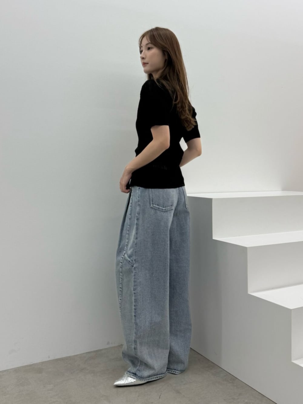 ブルー系のデニムパンツ、シルバー系のパンプス、ブラック系のニット/セーターを着用したレディースの春コーディネートの2枚目の写真