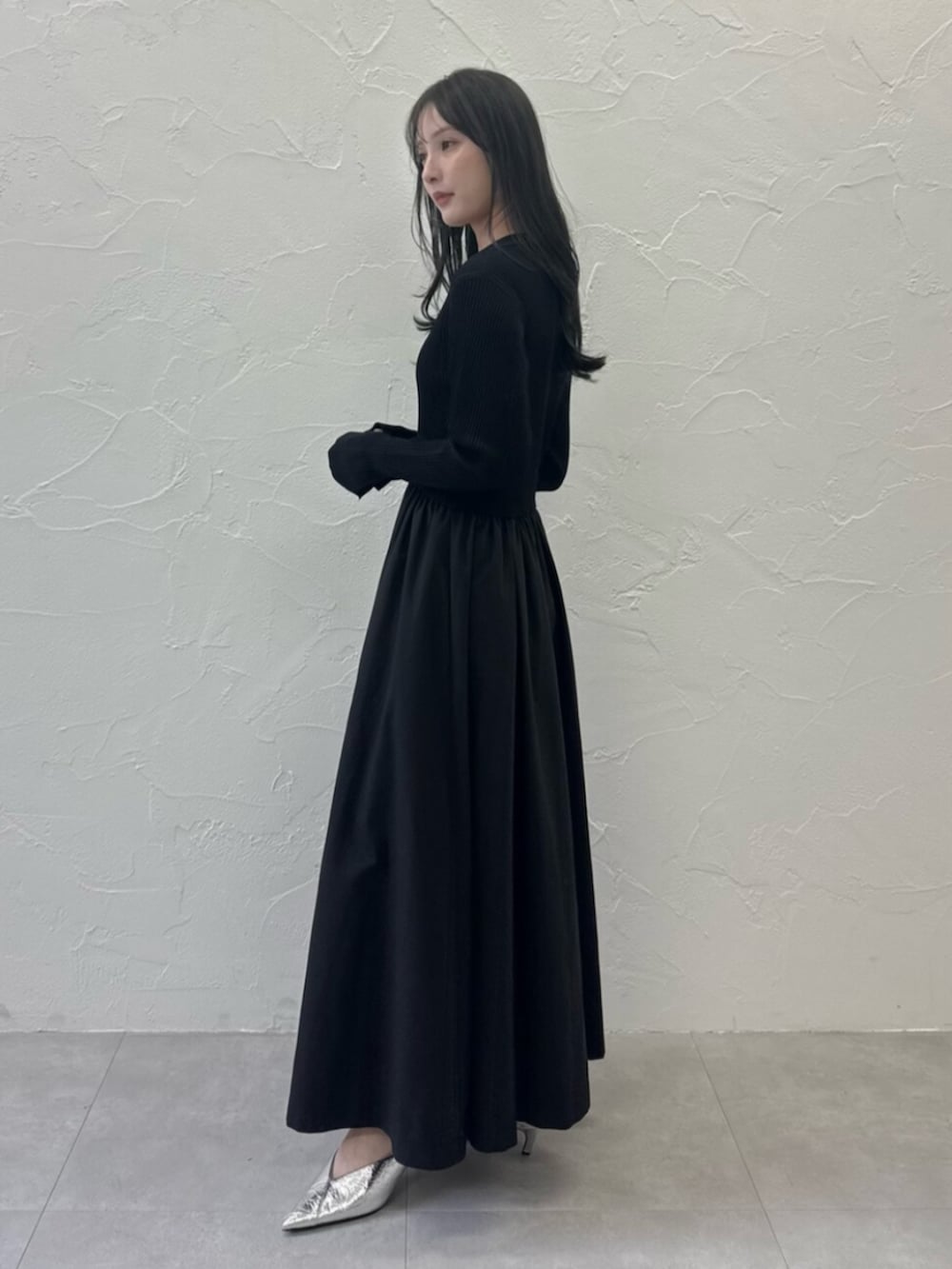 シルバー系のパンプス、ブラック系のワンピースを着用したレディースの春コーディネートの2枚目の写真