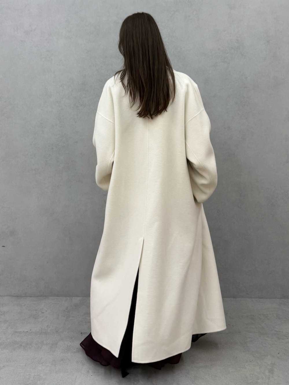 ホワイト系のチェスターコート、ホワイト系のニット/セーター、レッド系のスカートを着用したレディースの秋コーディネートの4枚目の写真